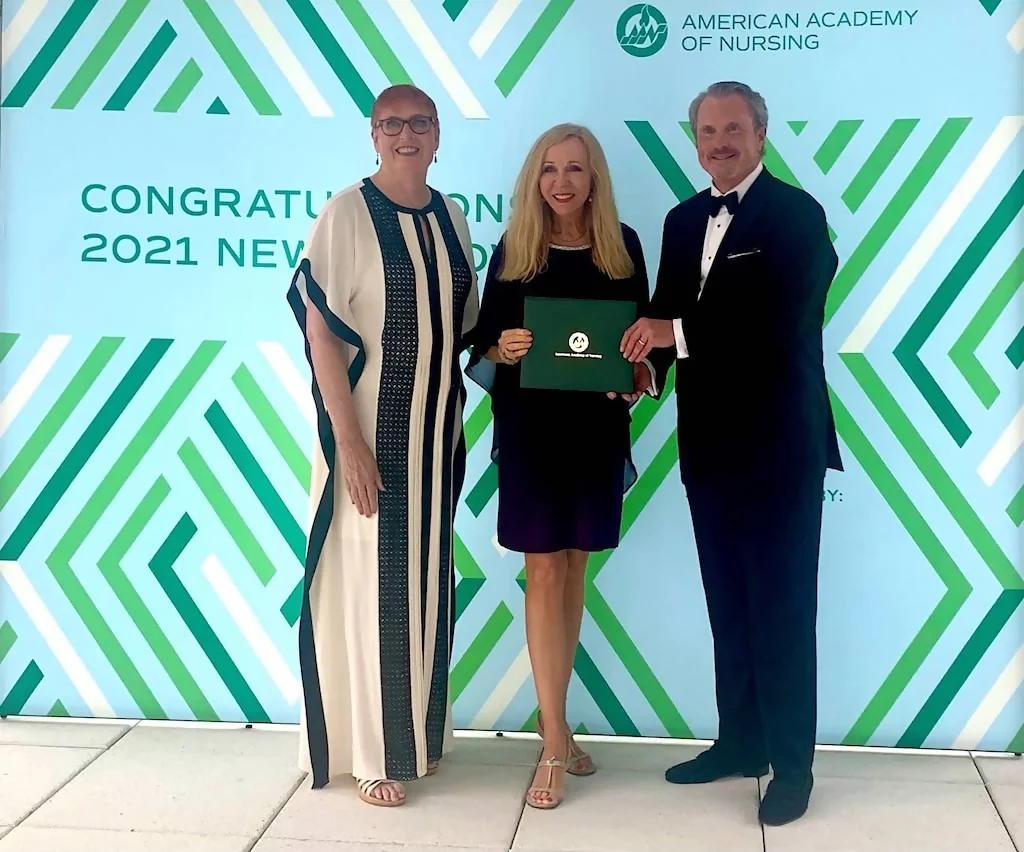 Three people standing in front of a wall with words " congratulations to the new class of 2 0 2 1 ".